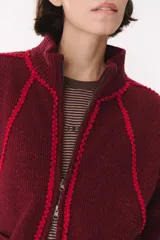 Campera de tejido de punto color marrón con destellos de lurex, corte oversize y cierre frontal. Presenta detalles de costuras y terminaciones en color crema, cuello alto y bolsillos frontales.