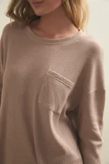 Conjunto de pijama compuesto por una remera de manga larga con bolsillo frontal y un pantalón de corte recto, ambos confeccionados en tejido de punto acanalado.