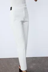 Pantalón de tiro medio con cintura elástica en la parte posterior. Cuenta con bolsillos delanteros, falsos bolsillos de vivo en la parte trasera y aberturas laterales en el bajo. Cierre frontal con cremallera, botón interior y gancho.