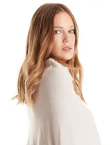 Poncho tejido de punto con diseño asimétrico y aberturas laterales para los brazos.