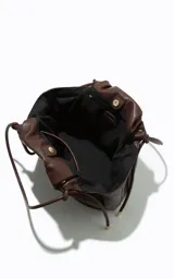 Cartera tipo tote de gran tamaño color chocolate, con diseño flexible y cierre de cordón ajustable. Presenta un acabado liso y minimalista con el logo de la marca grabado en la parte frontal.