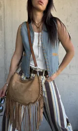 Chaleco de denim celeste sin mangas, con detalles de costuras decorativas en zig-zag y aplicaciones en tono suela en los bordes y bolsillos.