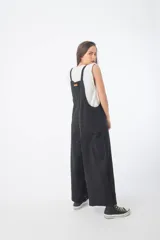 Mono negro de denim con corte oversize, breteles anchos y piernas anchas.