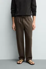 Pantalón de corte regular fit confeccionado en tejido mezcla de algodón, con cintura elástica ajustable mediante cordón, bolsillos laterales y bolsillos traseros de vivo.
