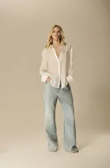 Camisa blanca de seda fluida con silueta relajada, mangas largas con puño simple y cuello clásico.