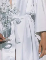 Kimono largo de seda blanca con mangas amplias y cinturón ajustable del mismo género.
