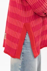 Buzo de tejido de punto con cuello alto, manga larga y diseño a rayas horizontales en tonos fucsia y naranja.