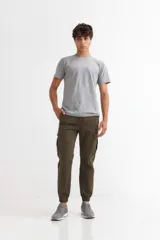 Pantalón tipo jogger cargo de hombre, color verde militar, con cordón ajustable en la cintura y puños elásticos en los tobillos. Presenta bolsillos cargo con solapa en ambos muslos.