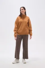 Buzo de algodón color tostado, con cuello polo y cierre frontal parcial con botones. Presenta un detalle de forro de corderito sintético blanco en el cuello y mangas largas con diseño holgado.