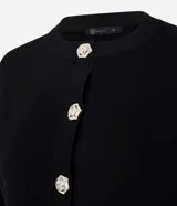 Cardigan de punto color negro, con cuello redondo, mangas largas y cierre frontal mediante botones metálicos con diseño de flores. Presenta puños y ruedo acanalados.