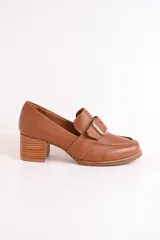 Mocasín de cuero color marrón con hebilla metálica plateada y taco de madera.