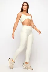 Calza larga deportiva de tiro alto en color marfil, confeccionada en tejido elástico con costuras drapeadas que realzan la figura.