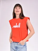 Remera naranja con cuello redondo y mangas cortas con hombreras. Estampado frontal con la palabra 'Soleil' en blanco.