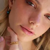 Anillo dorado de acero con diseño de borlas macizas de tamaño decreciente que se cruzan en el frente.