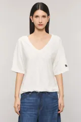 Remera oversize color blanco, confeccionada en jersey Pima flamé de algodón. Cuenta con escote en V, mangas cortas con detalle de bordado en la manga y cintura con elástico que genera un efecto balloon.