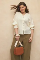 Bandolera de cuero sintético color marrón con correa de tela desmontable y regulable. Cuenta con un compartimento interno y dos bolsillos adicionales.