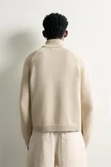 Chaqueta relaxed fit de punto tejido en hilatura con mezcla de algodón, color beige, con cuello subido y manga larga. Cuenta con acabados en rib, efecto lavado y cierre frontal con cremallera.