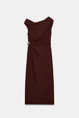 Vestido midi color bordó con escote asimétrico y manga sisa. Presenta frunces en el delantero con un aplique metálico dorado en forma de nudo.