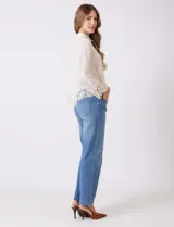 Camisa de algodón con bordado suizo, cuello con solapa y cierre frontal con botones. Presenta mangas largas con terminación de encaje calado y un ruedo asimétrico en pico con un amplio galón de encaje.