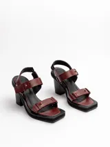 Sandalias negras de cuero vacuno con tiras, detalles de gemelos en bronce, taco de madera y plataforma de EVA.