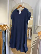 Vestido midi azul marino de lino, corte recto, con cuello en V, mangas cortas y detalle de flecos en ruedo y mangas.