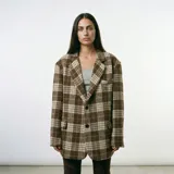 Blazer de corte oversize con estampado de cuadros en tonos marrones y beige, con solapas clásicas, cierre frontal de dos botones y bolsillos laterales con solapa.