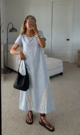 Vestido largo celeste con mangas cortas, escote redondo y detalles de pasamanería geométrica en los laterales de la falda.