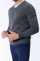 Buzo de punto gris melange con escote en V, de manga larga y puños acanalados.