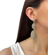 Aros colgantes largos con forma ovalada, recubiertos de hilos brillantes color dorado.