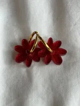 Aros de argolla metálica con dije colgante en forma de flor de acrílico color rosado.