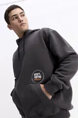 Canguro con capucha y cordones ajustables en color beige, con diseño de calce regular y estampado frontal pequeño.