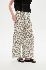 Pantalón de algodón estampado con diseño botánico de hojas en tonos verdes sobre base blanca, de corte holgado, tiro medio y cintura elástica con cordón de ajuste ajustable.