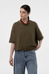 Remera verde militar de corte holgado y diseño amplio, con mangas cortas, hombros caídos, largo levemente cropped y detalle de broderie en el frente.