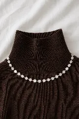 Collar corto tipo gargantilla compuesto por pequeñas flores de nácar intercaladas con cuentas doradas.