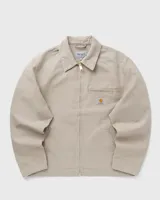 Campera Carhartt modelo Detroit color beige, con cuello camisero, cierre frontal con cremallera, bolsillos laterales y bolsillo en el pecho con logo de la marca.