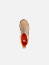 Bota tipo Chelsea de cuero beige con paneles laterales elásticos en color crema y detalles en naranja. Cuenta con una suela de caucho dentada color caramelo y tacón cuadrado.