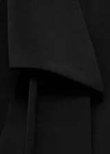 Vestido corto de color negro con escote cruzado en V y cuello con solapa. Presenta mangas largas con puños abotonados, pliegues decorativos en la cintura y un lazo desmontable en el cuello.