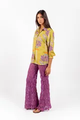 Camisa de manga larga con cuello clásico y cierre frontal de botones, confeccionada en tejido de color verde lima con estampa floral en tonos morados y naranjas.