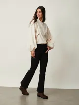 Pantalón de jean negro de corte flare, con tiro medio y bolsillos delanteros y traseros.