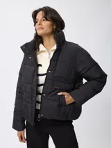 Campera puffer de nylon color negro, con cuello alto, cierre frontal con cremallera y botones a presión. Presenta bolsillos frontales con solapa y diseño acolchado.