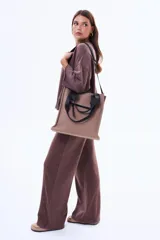 Bolso tipo tote color marrón, con diseño minimalista y moderno. Cuenta con asas de mano negras, correa ajustable para el hombro y un bolsillo frontal con cierre.