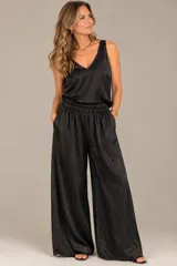 Pantalón palazzo negro de seda satinada, con cintura elástica fruncida y bolsillos laterales, de corte amplio y fluido.