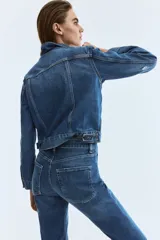 Jean de cinco bolsillos en denim de algodón con stretch. Modelo bootcut de tiro alto, ajustado de cintura a cadera y con corte ligeramente acampanado desde la rodilla hacia el bajo. Presenta raya marcada en la parte delantera y trasera.