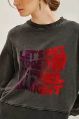 Buzo de cuello redondo y manga larga, confeccionado en algodón y viscosa con efecto lavado. Presenta un estampado frontal con tipografía en tonos degradados de violeta a rojo.