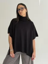 Poncho de tejido de punto color marrón chocolate, con cuello alto tipo polera y mangas cortas amplias. Presenta un diseño holgado con terminaciones acanaladas en el ruedo.