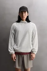 Sudadera regular fit de tejido polar con textura efecto pelo, color gris claro. Cuenta con cuello subido, capucha ajustada, manga larga ranglán, bolsillos laterales en la cadera y bajo asimétrico más largo en la espalda. Los acabados son con cinta elástica.