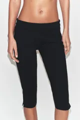 Pantalón capri de tiro medio confeccionado en tejido elástico, con cierre lateral mediante cremallera oculta.