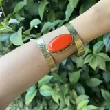 Brazalete dorado con textura, con piedra ágata ovalada color naranja.