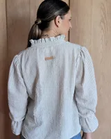 Blusa de algodón con cuello mao y volados, mangas largas con puños elásticos y corte holgado.