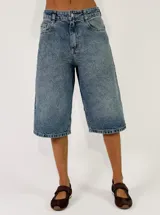 Bermuda de denim azul con lavado medio, tiro alto y diseño amplio de corte recto hasta las rodillas.